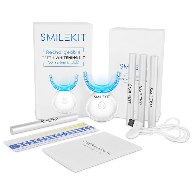 Kit blanqueamiento dental: luz LED azul, 4 aplicadores de gel, guía de tonos y cable cargador sobre fondo blanco.
