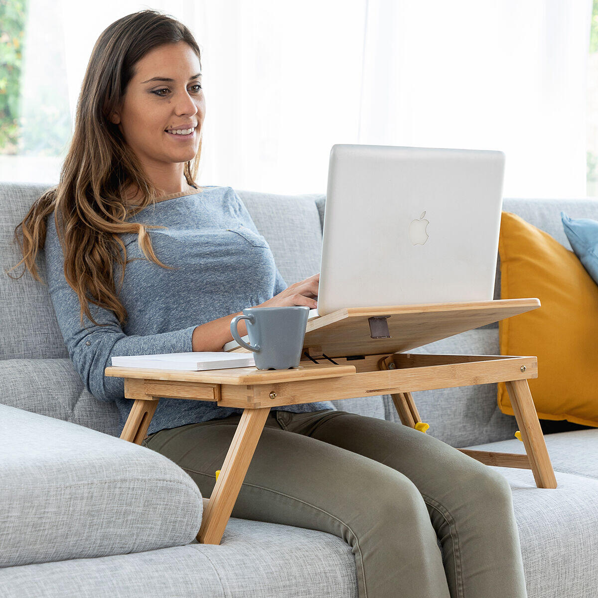 Mujer usando Mesa plegable auxiliar de bambú Lapwood InnovaGoods para sofá y cama