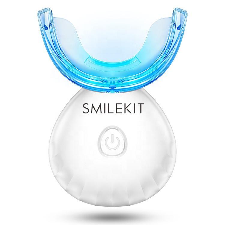 Kit de blanqueamiento dental con férula azul LED y base blanca recargable con botón de encendido sobre fondo blanco.