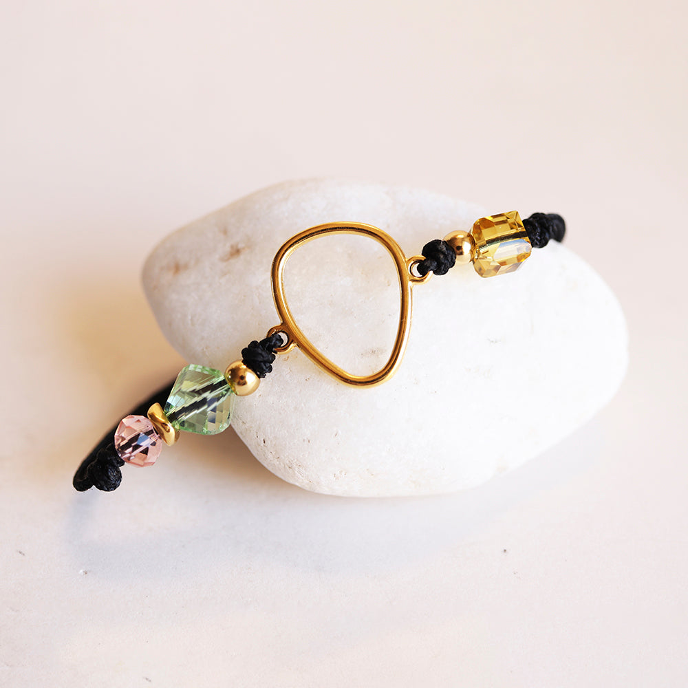 Pulsera de macramé negra con cuentas de cristal amarillo, verde y rosado en forma de lágrima dorada.