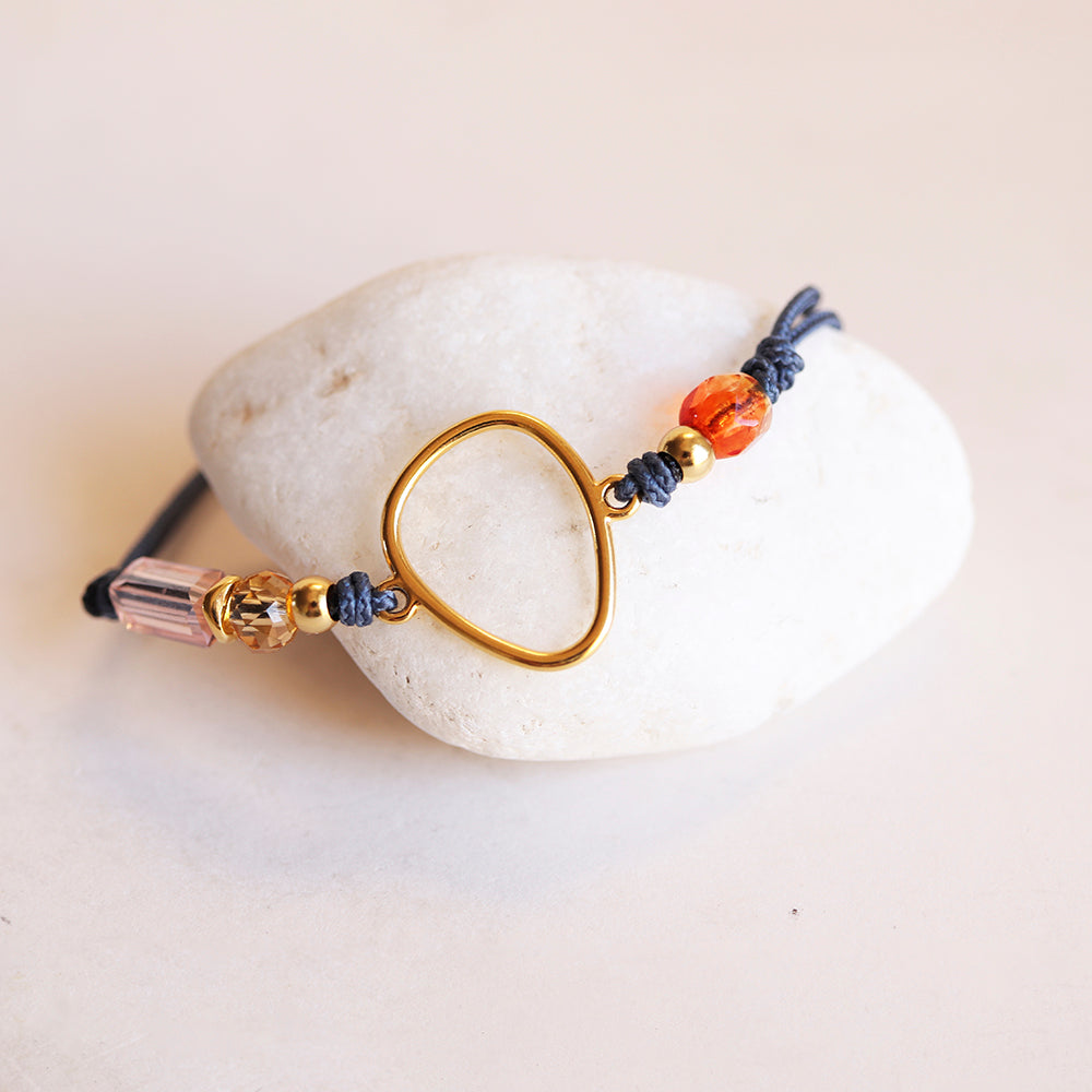 Pulsera de hilo azul con adorno dorado y cuentas de cristal naranja y rosa. Estilo bohemio.