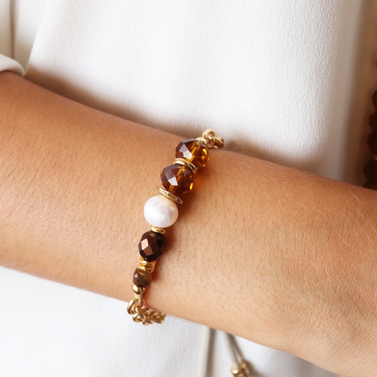 Pulsera de cuentas marrones y perla, con detalles en dorado, estilo elegante y moderno. Ideal para cualquier ocasión.