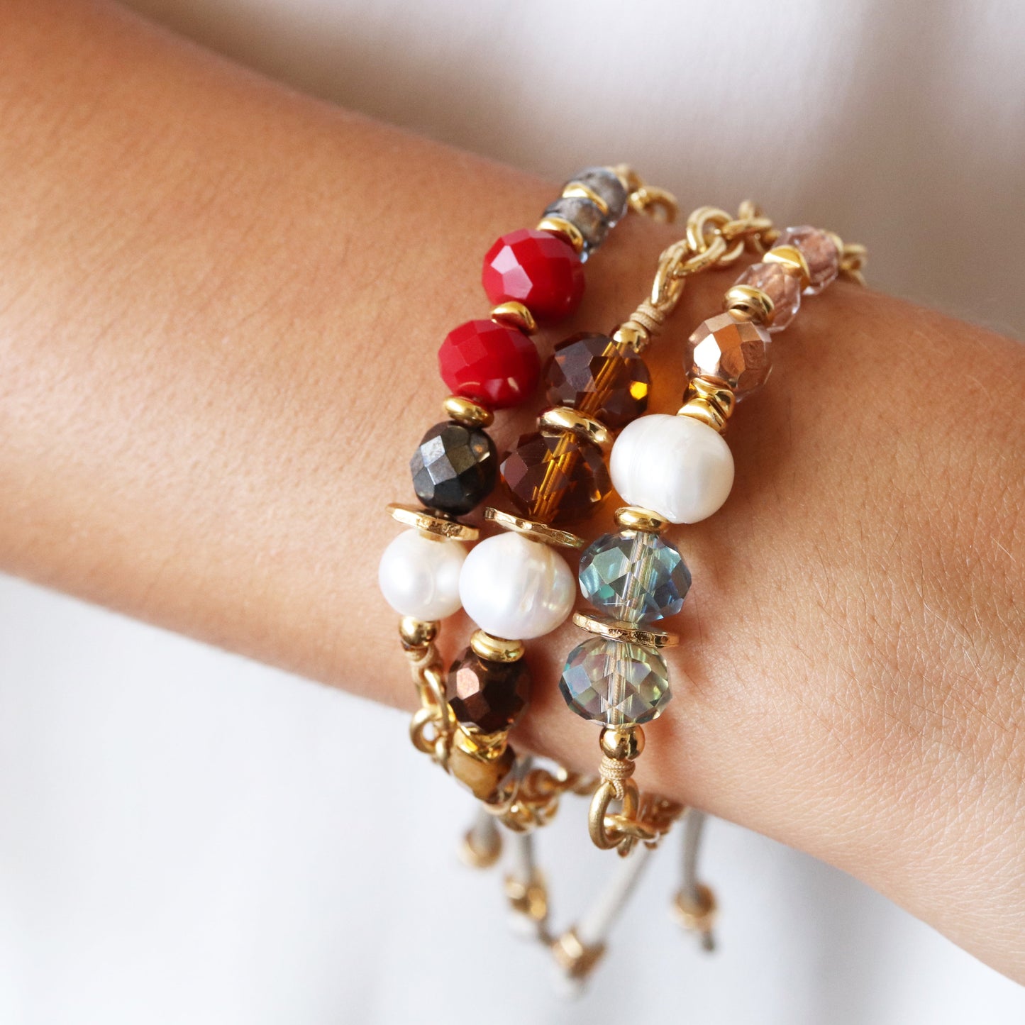 Pulsera de cuentas rojas, negras y doradas con perlas y cristales, estilo bohemio y materiales de alta calidad.