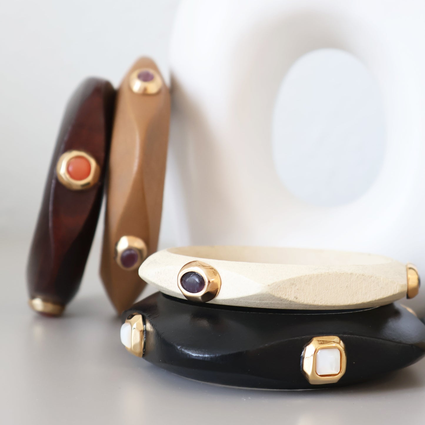 Brazaletes de resina en tonos marrón, negro y blanco, con gemas en dorado, estilo moderno y elegante.