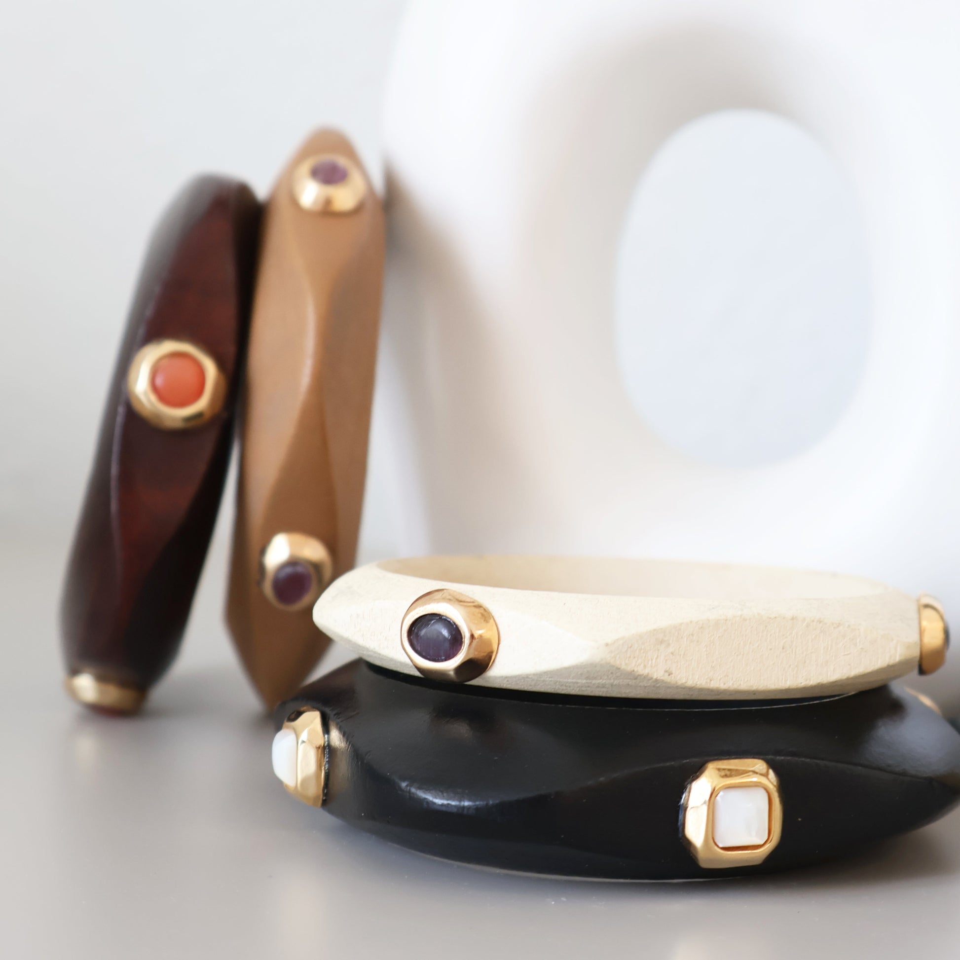 Brazaletes de resina en tonos marrón, negro y blanco, con gemas en dorado, estilo moderno y elegante.