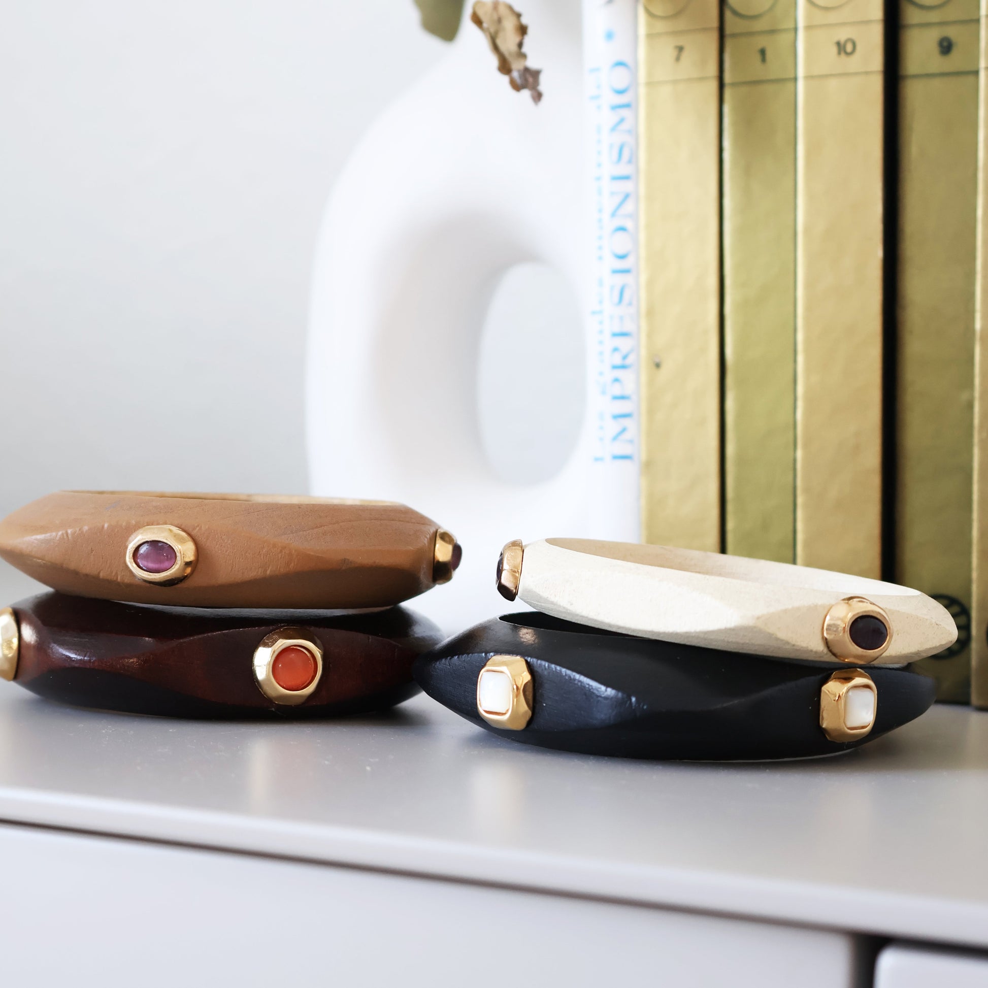 Pulseras de madera en tonos beige, marrón y negro con piedras preciosas, estilo elegante y moderno.