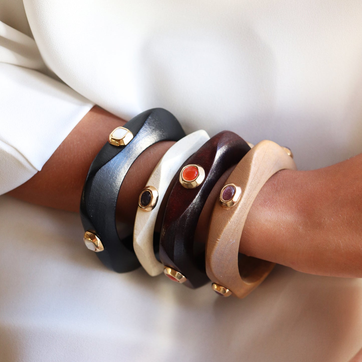 Brazaletes de cuero en negro, blanco, marrón y beige con piedras preciosas y detalles dorados.