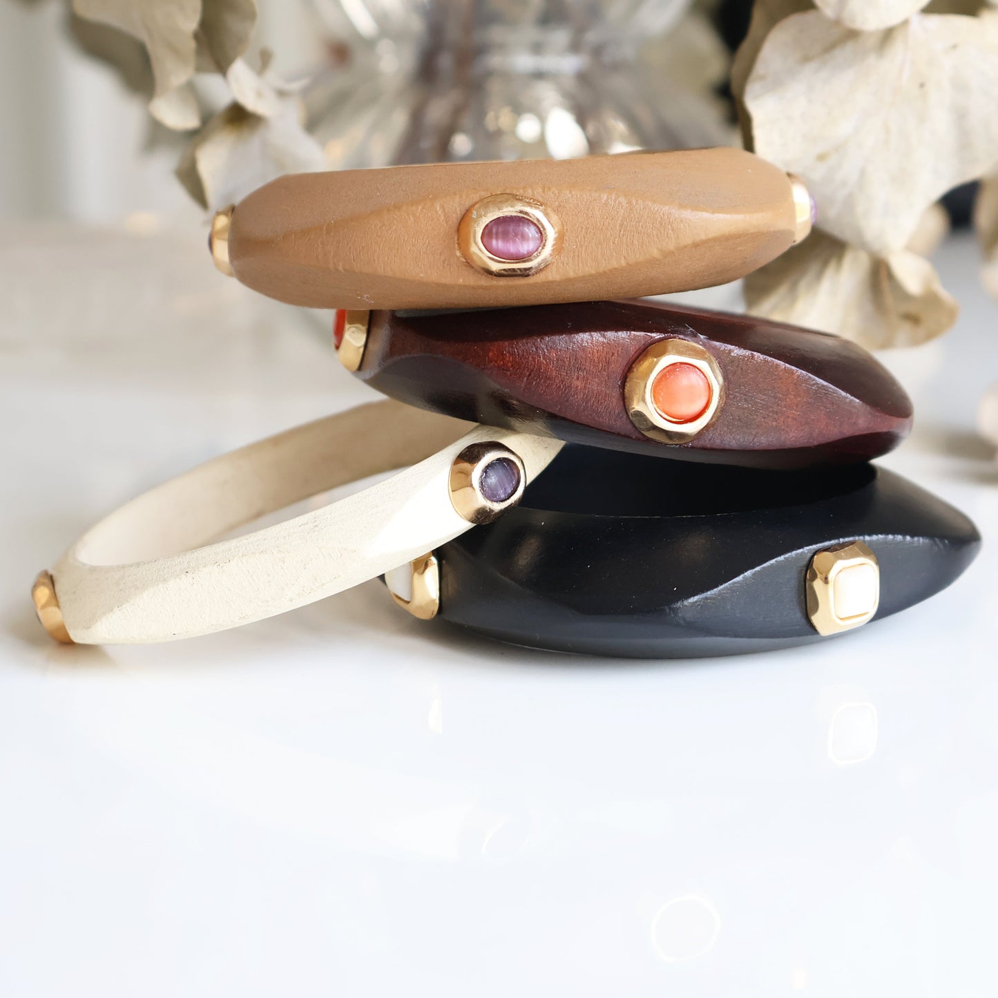 Pulseras de cuero en tonos marrón, negro, crema y vino, con gemas decorativas y detalles dorados.