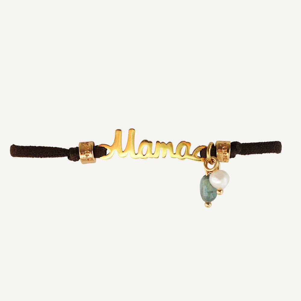 Pulsera 'Mama' en dorado, con encanto de perla y piedra verde, sobre banda de tela negra. Perfecta para regalar.