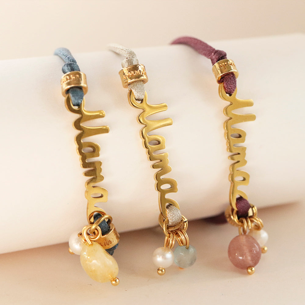 Pulsera "Mama" dorada con cuentas de piedras preciosas, disponible en azul, gris y púrpura, estilo moderno y elegante.