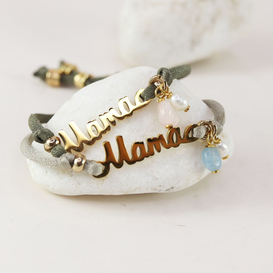 Pulsera "Mamá" dorada en metal con cuentas de perlas y piedras, cordón verde oliva, estilo moderno y elegante.