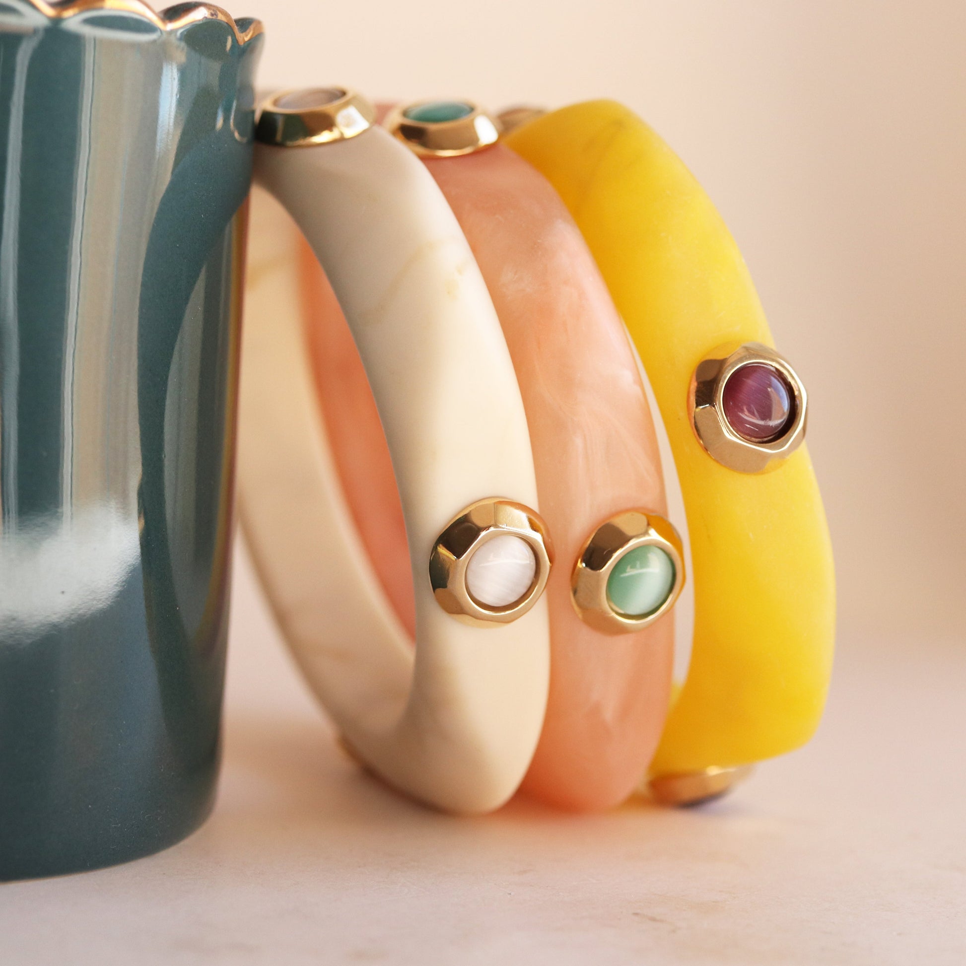Brazaletes de colores (amarillo, rosa, crema) con detalles dorados y piedras preciosas, ideal para un estilo elegante.