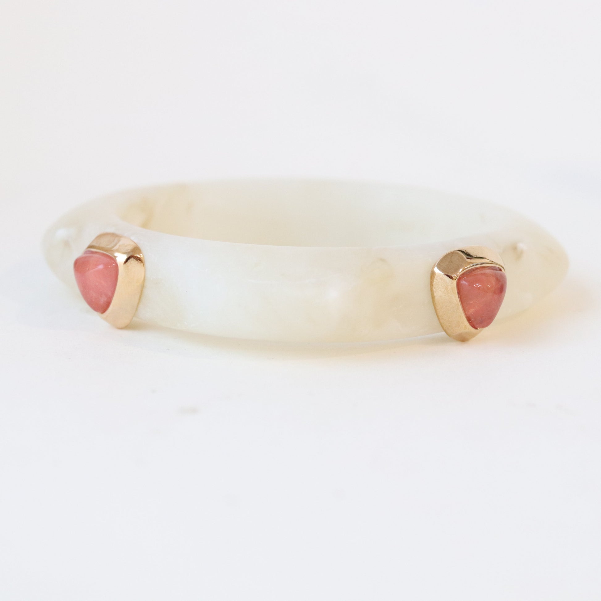 Pulsera de jade blanco con gemas rosas, detalle en oro, estilo elegante y moderno.
