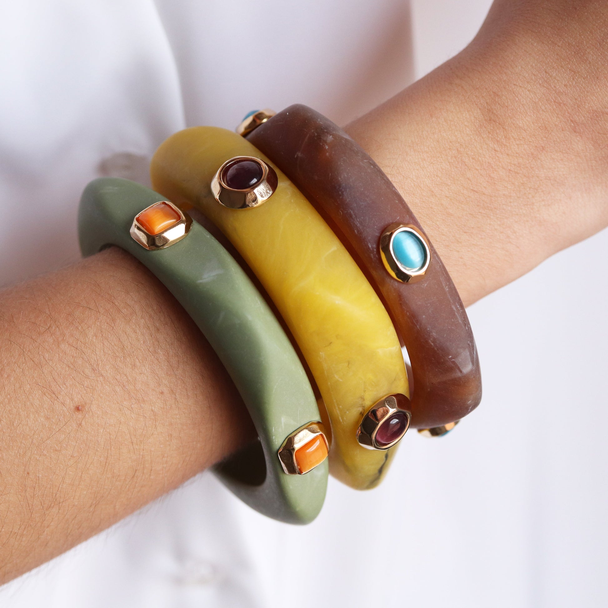 Brazaletes de resina en colores verde, amarillo y marrón con piedras semi-preciosas en dorado. Estilo moderno y elegante.