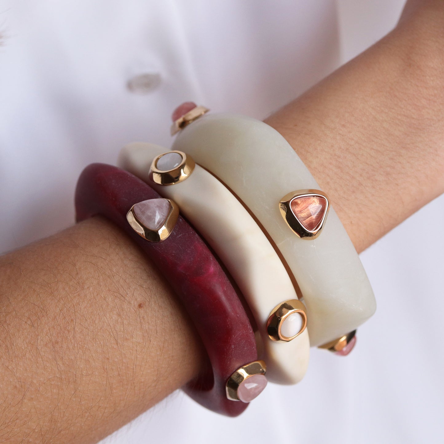 Pulseras de resina en rojo y blanco con detalles en dorado y piedras preciosas, estilo moderno y elegante.