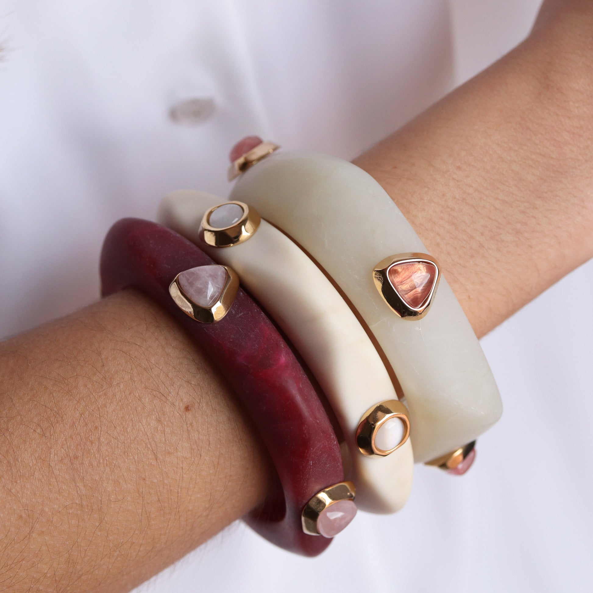 Pulseras de resina en rojo y blanco con detalles en dorado y piedras preciosas, estilo moderno y elegante.