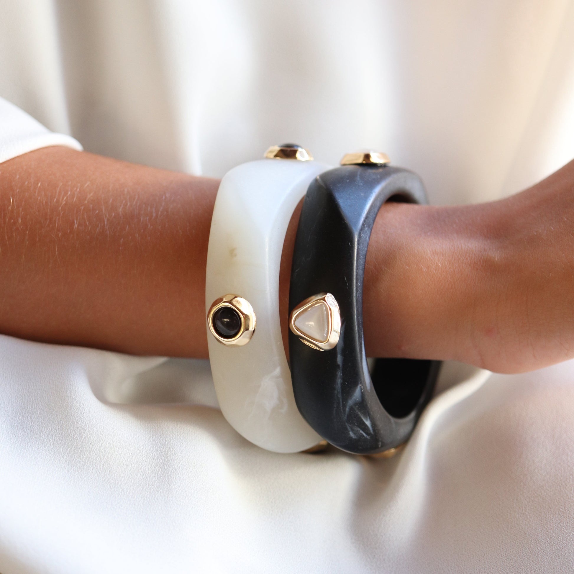 Pulseras de resina negra y blanca con detalles dorados en un estilo moderno y elegante.
