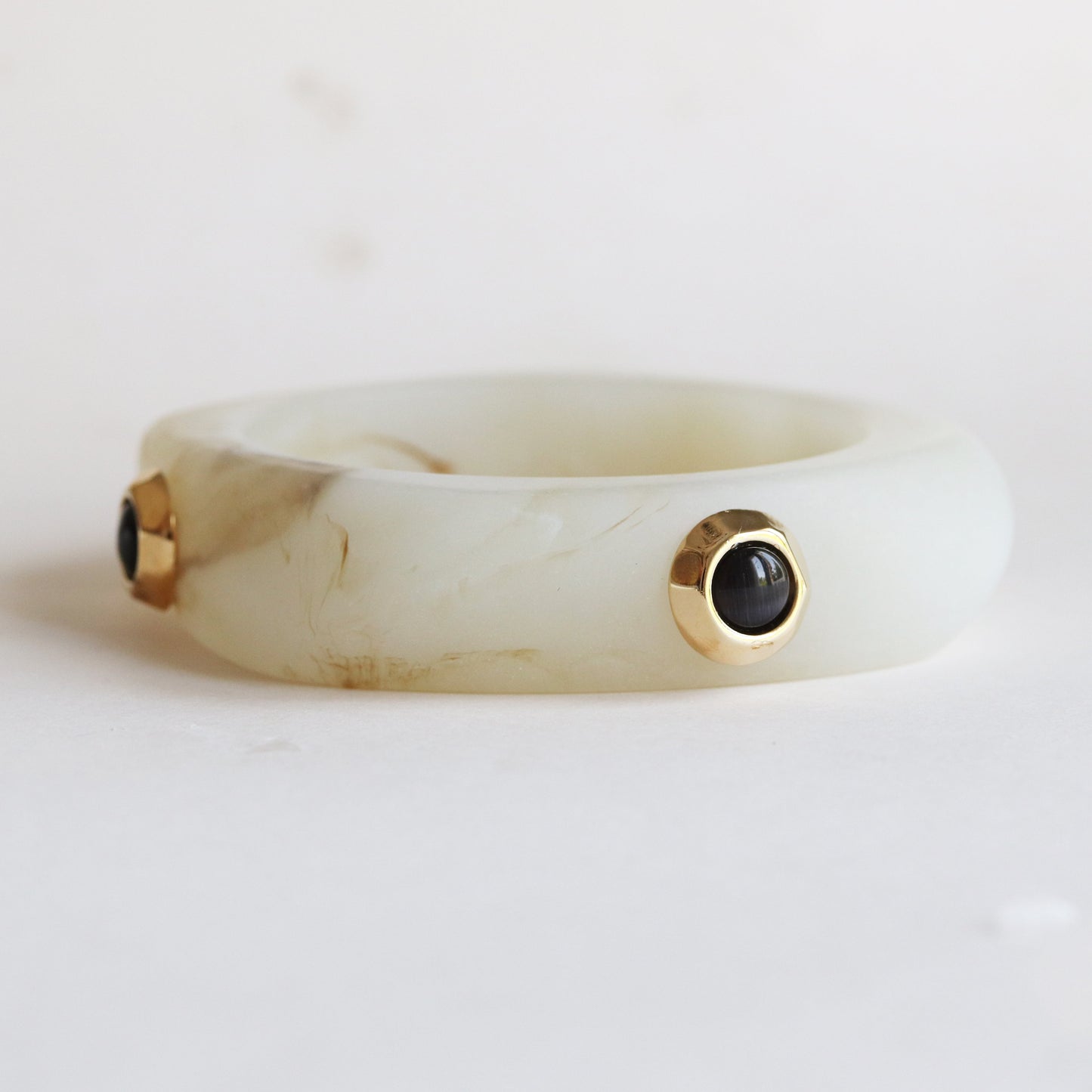 Brazalete de resina verde claro con detalles en oro y gemas negras, estilo moderno y elegante.
