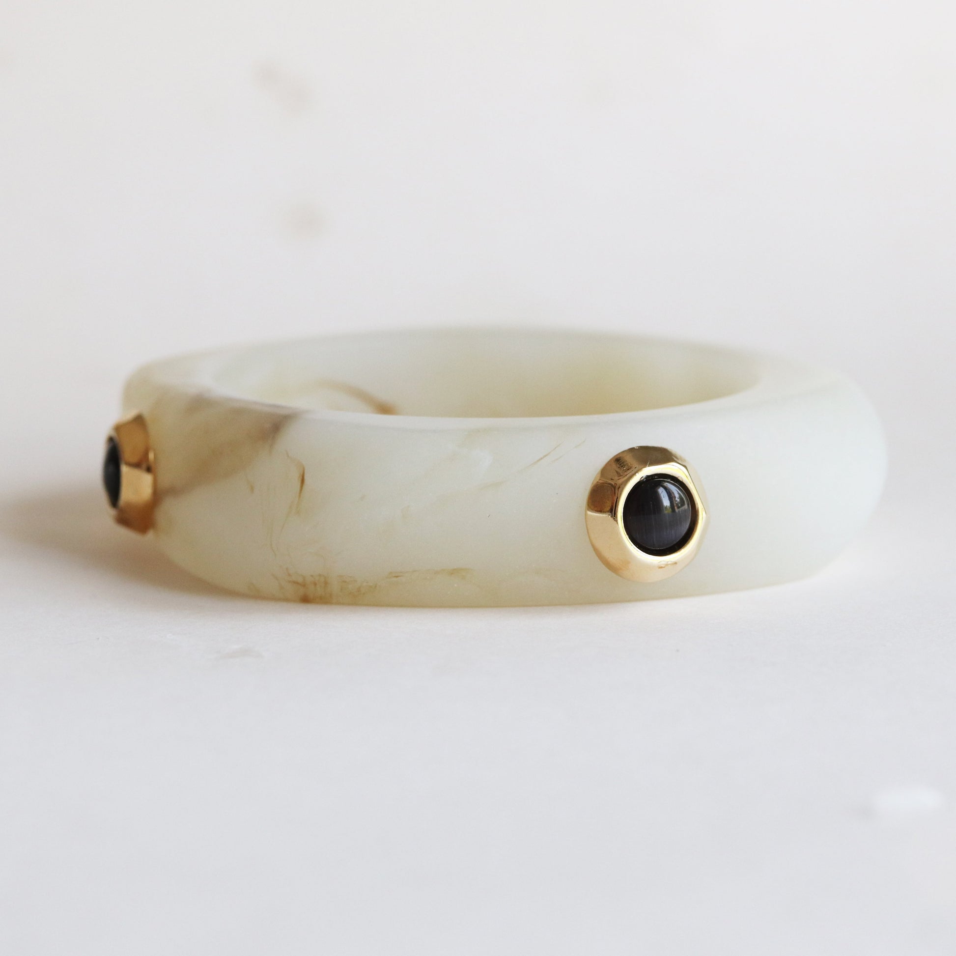 Brazalete de resina verde claro con detalles en oro y gemas negras, estilo moderno y elegante.