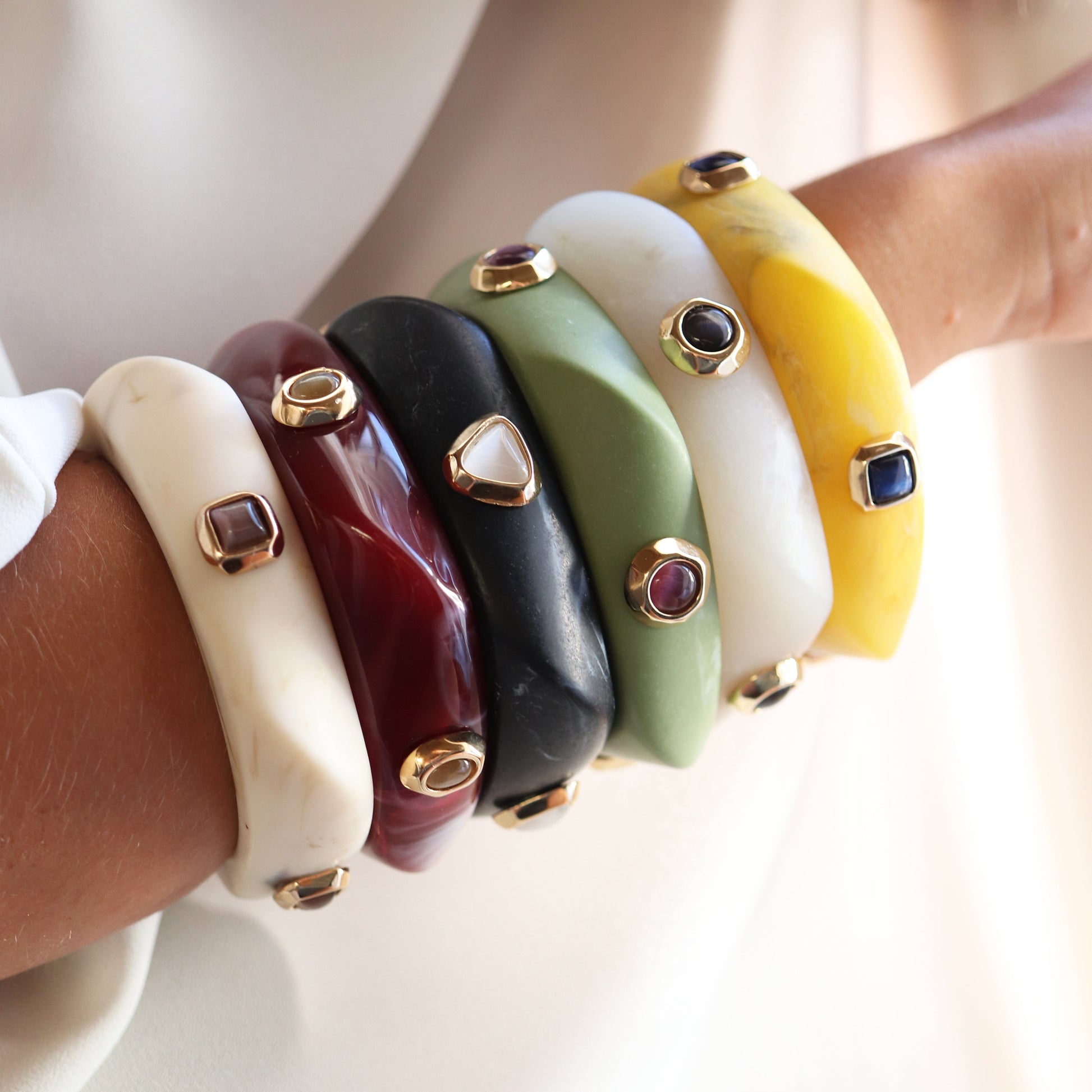 Pulseras de resina en colores rojo, negro, verde, amarillo y blanco con detalles dorados y gemas decorativas.