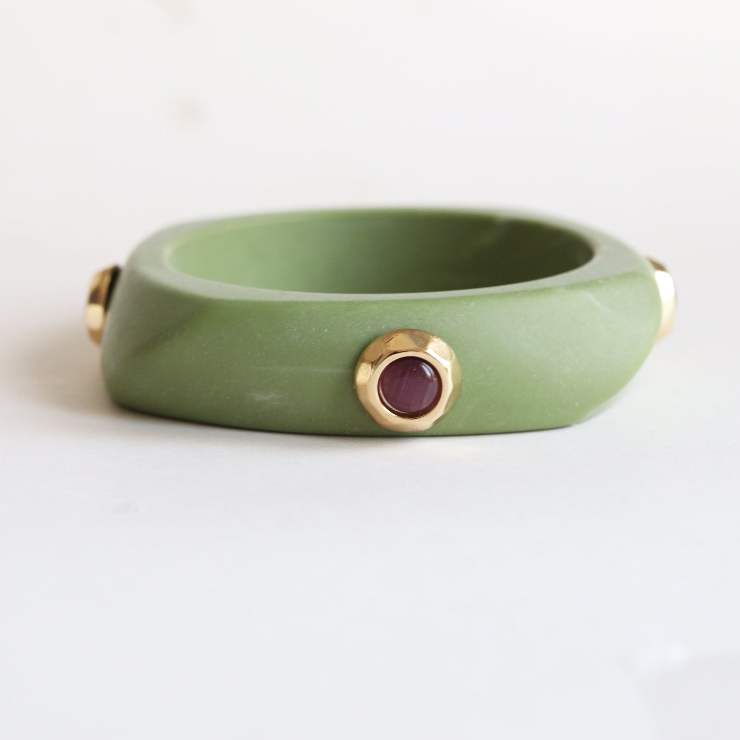 Pulsera verde jade con detalles dorados y piedra roja, estilo moderno y elegante para accesorios de moda.