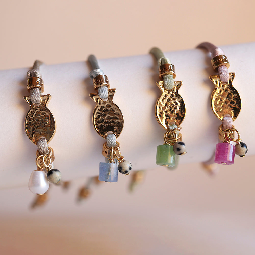 Pulseras de colores pastel con adornos dorados y piedras naturales, estilo bohemio y elegante.
