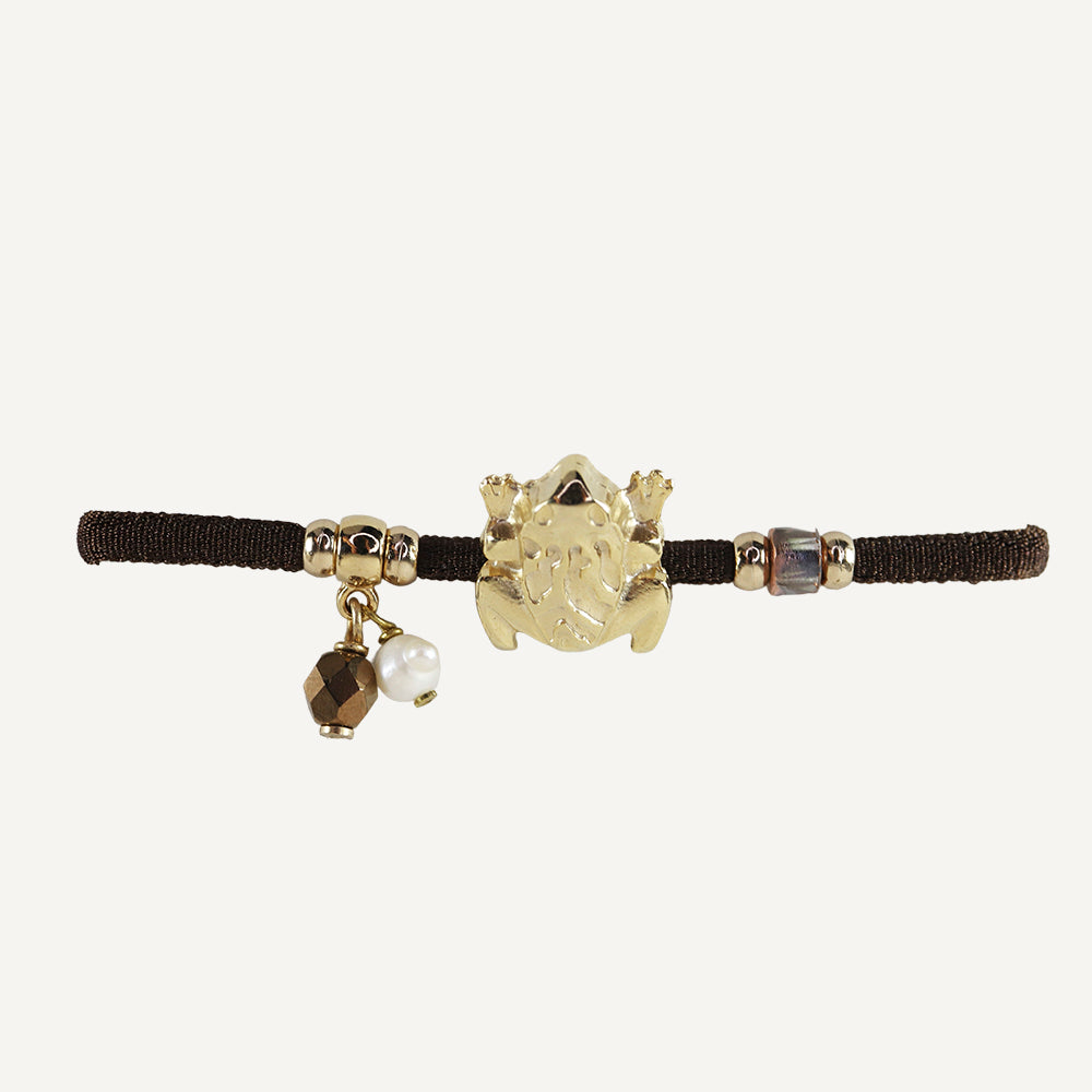Diadema negra con accesorios dorados, perlas y figura de rana, ideal para un look elegante y divertido.