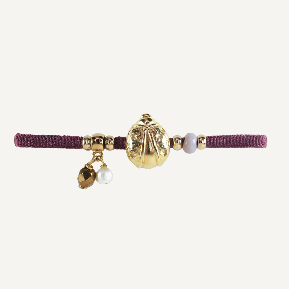 Diadema morada con adornos dorados, perlas y piedras, estilo elegante y bohemio.