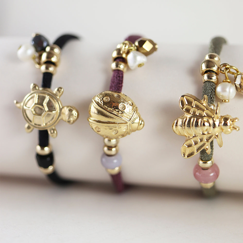 Pulseras de cuerda en tonos negro, burdeos y gris con charm de tortuga, mariquita y abeja en dorado.
