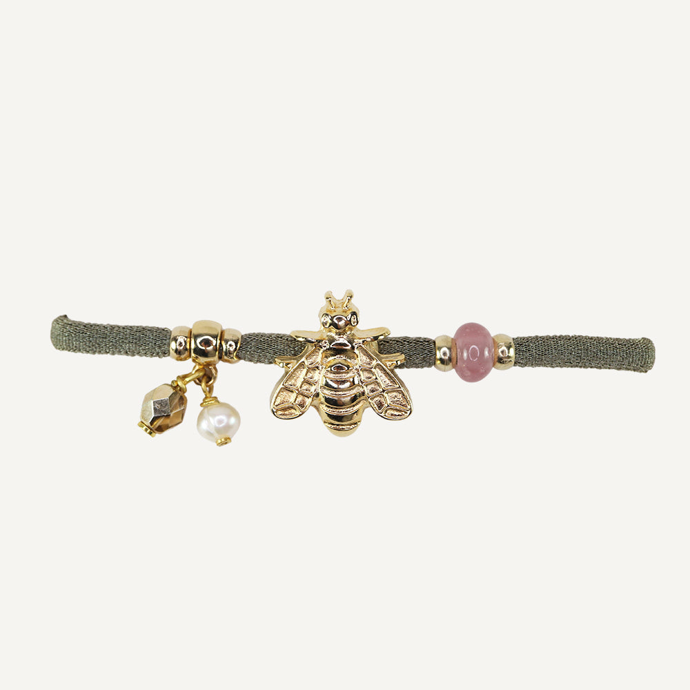 Pulsera de tela verde con abeja dorada y cuentas de perlas y piedra rosa, estilo elegante y moderno.