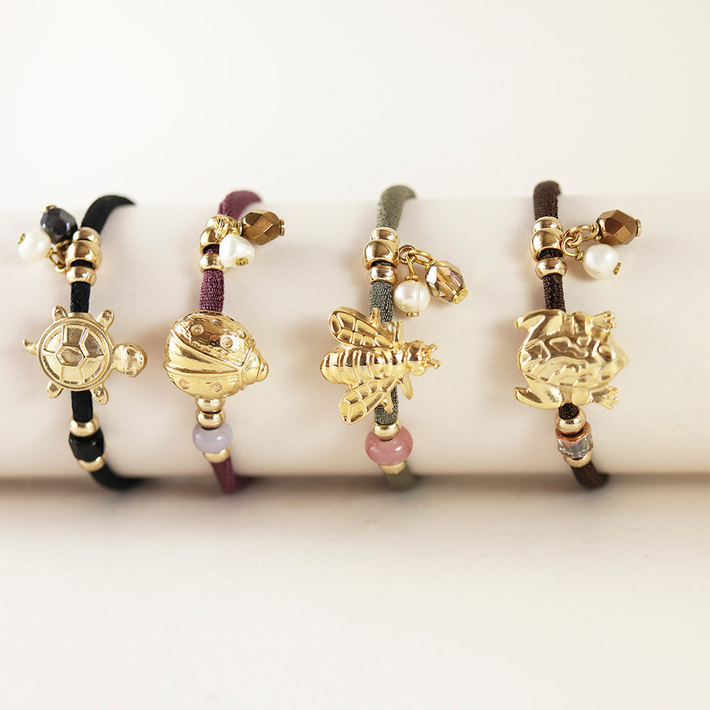 Pulseras de hilo en tonos negro, gris, marrón y rosa con charm dorado de tortuga, pez, abeja y dragón.