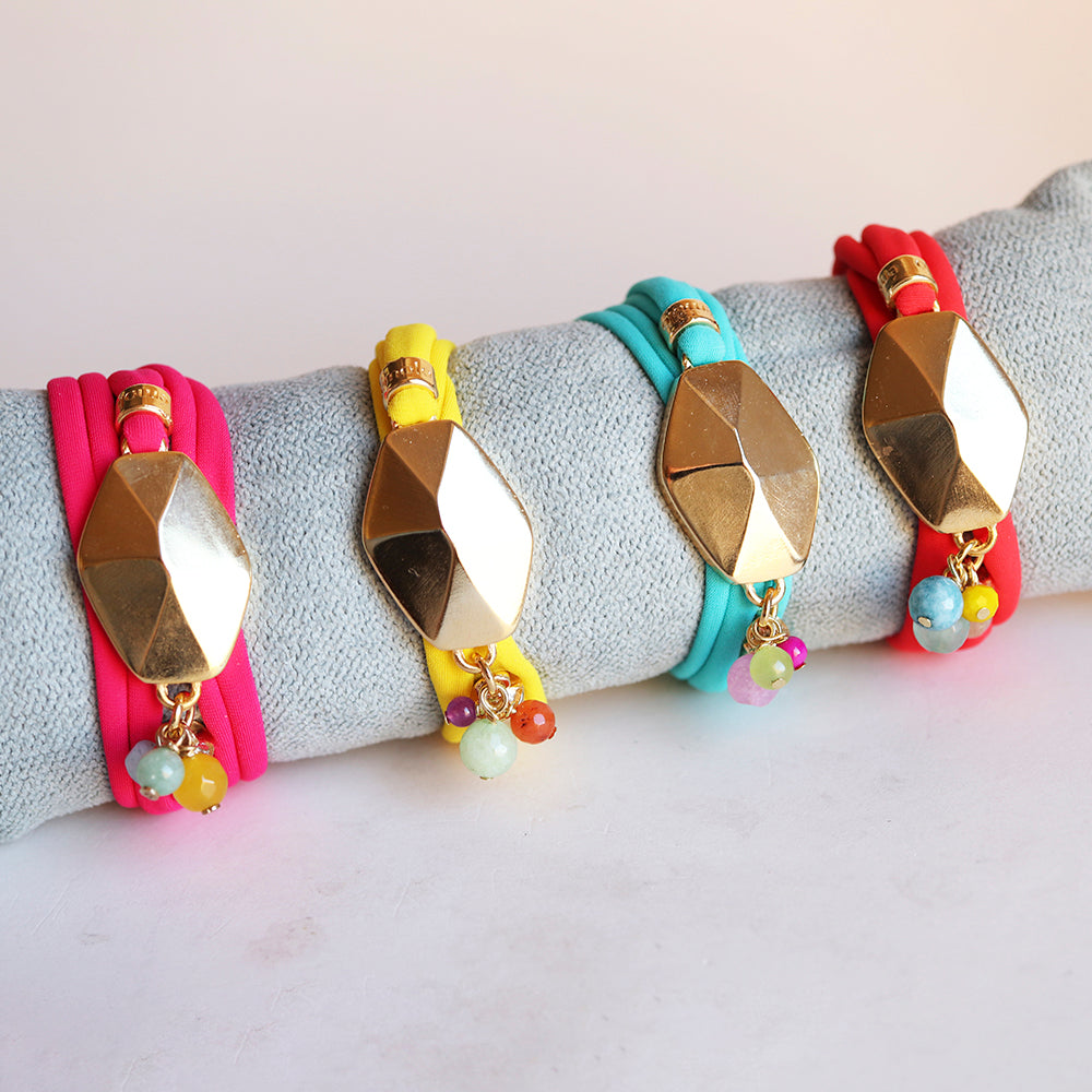 Pulsera de silicona en rosa, amarillo y azul con detalles dorados y cuentas coloridas. Estilo moderno y vibrante.