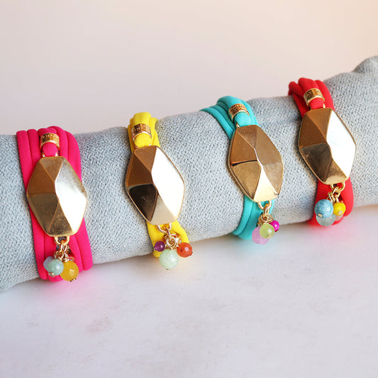 Pulsera de silicona en rosa, amarillo y azul con detalles dorados y cuentas coloridas. Estilo moderno y vibrante.