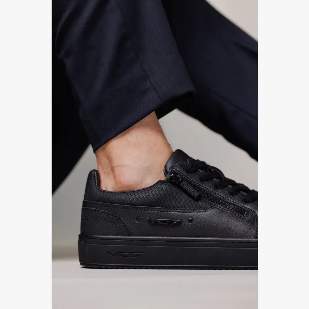 Baskets VO7 Roma Snake Dark en cuir noir à motif écailles, avec fermeture éclair latérale et semelle noire assortie.