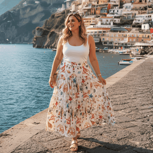 Woman wearing a tiered white 100% cotton maxi skirt with a colorful seashell and starfish print by the ocean.