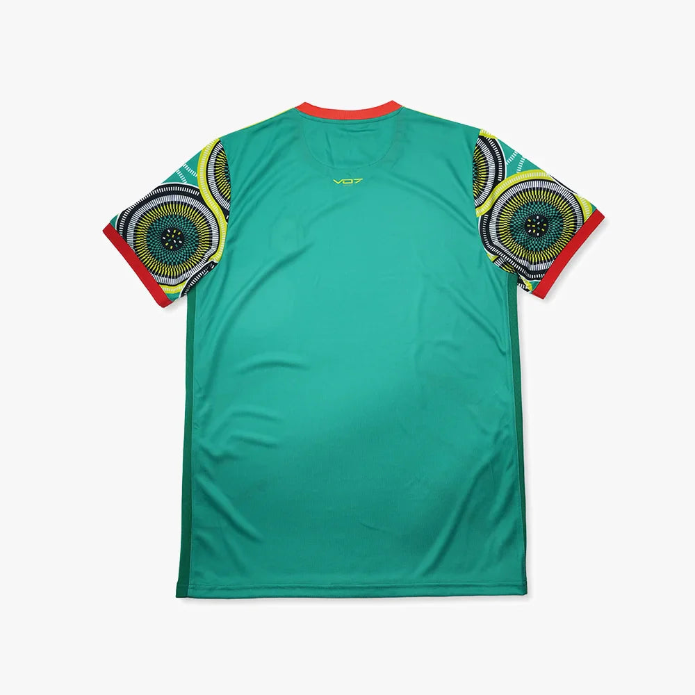 Maillot de foot VO7 vert à manches courtes avec motifs circulaires colorés, col et bords de manches rouges.