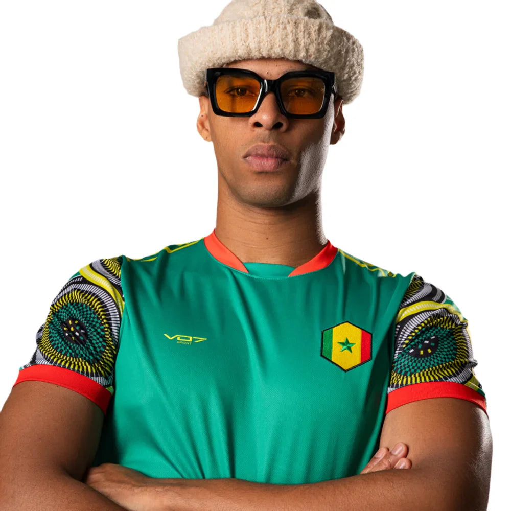 Maillot vert VO7 du Sénégal à manches à motifs africains colorés, col orange et écusson hexagonal sur la poitrine.