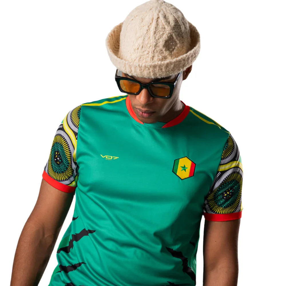 Maillot VO7 vert à motifs africains sur les manches, col rouge et écusson du Sénégal sur la poitrine.