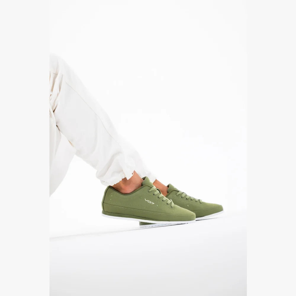 Baskets VO7 Yacht 10 kaki en toile avec semelle blanche, portées avec un pantalon blanc sur fond neutre.