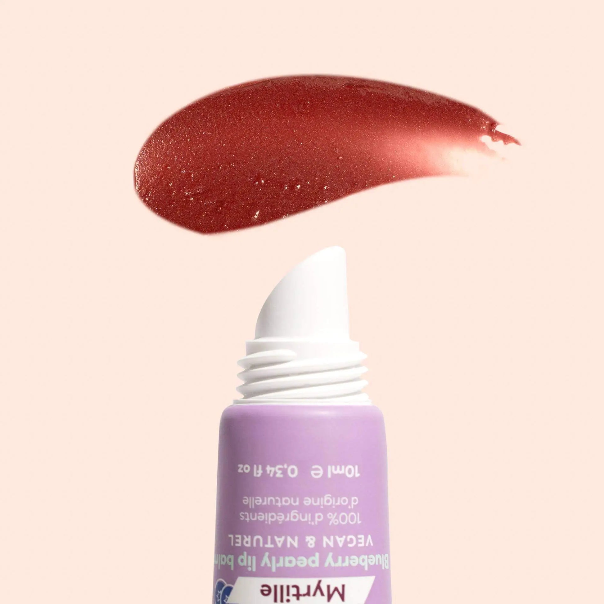A lavender tube of blueberry lip balm with a slanted white tip and a glossy, berry-colored product swatch above it.