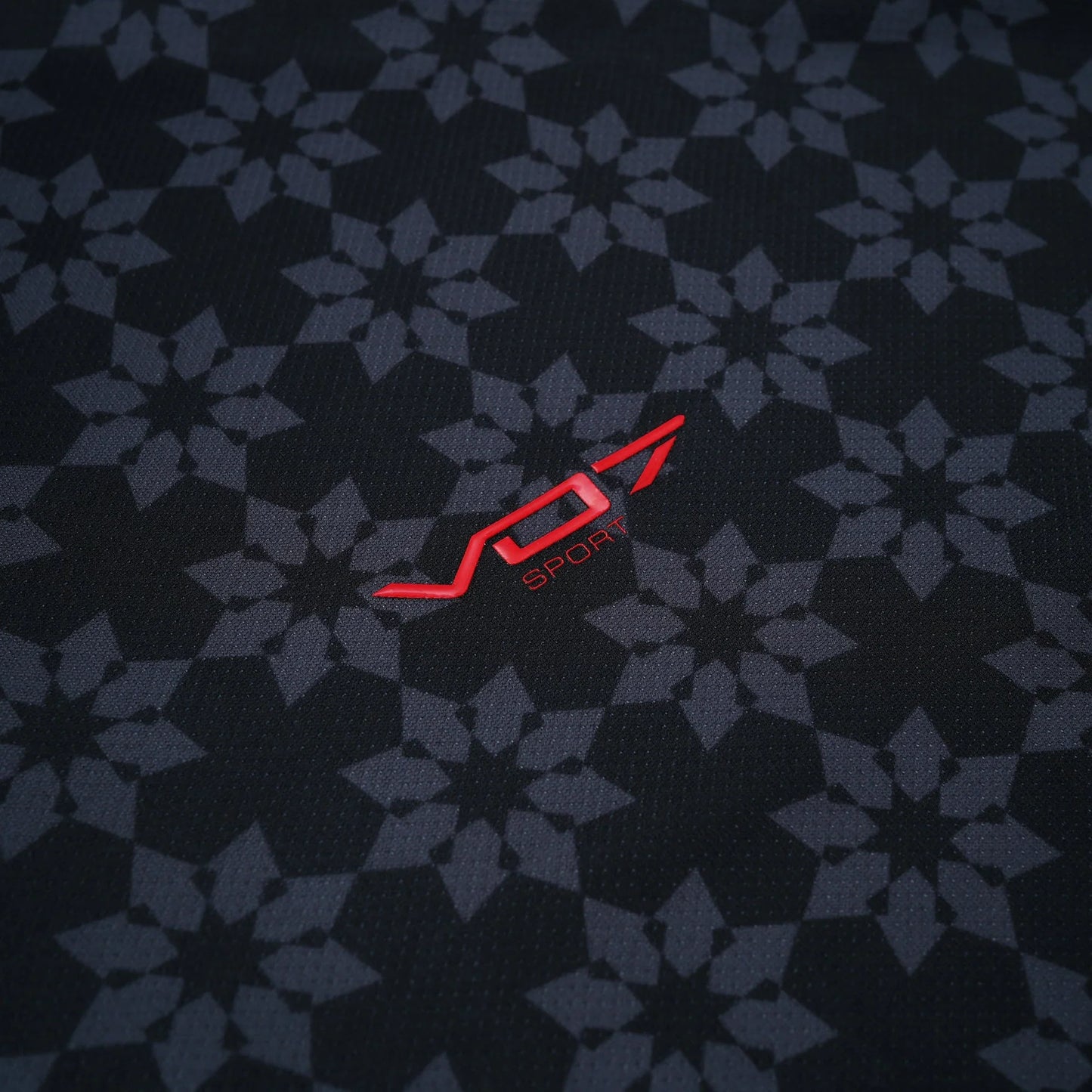 Maillot VO7 noir en tissu technique à motifs géométriques gris, avec logo VO7 SPORT rouge contrastant en relief.