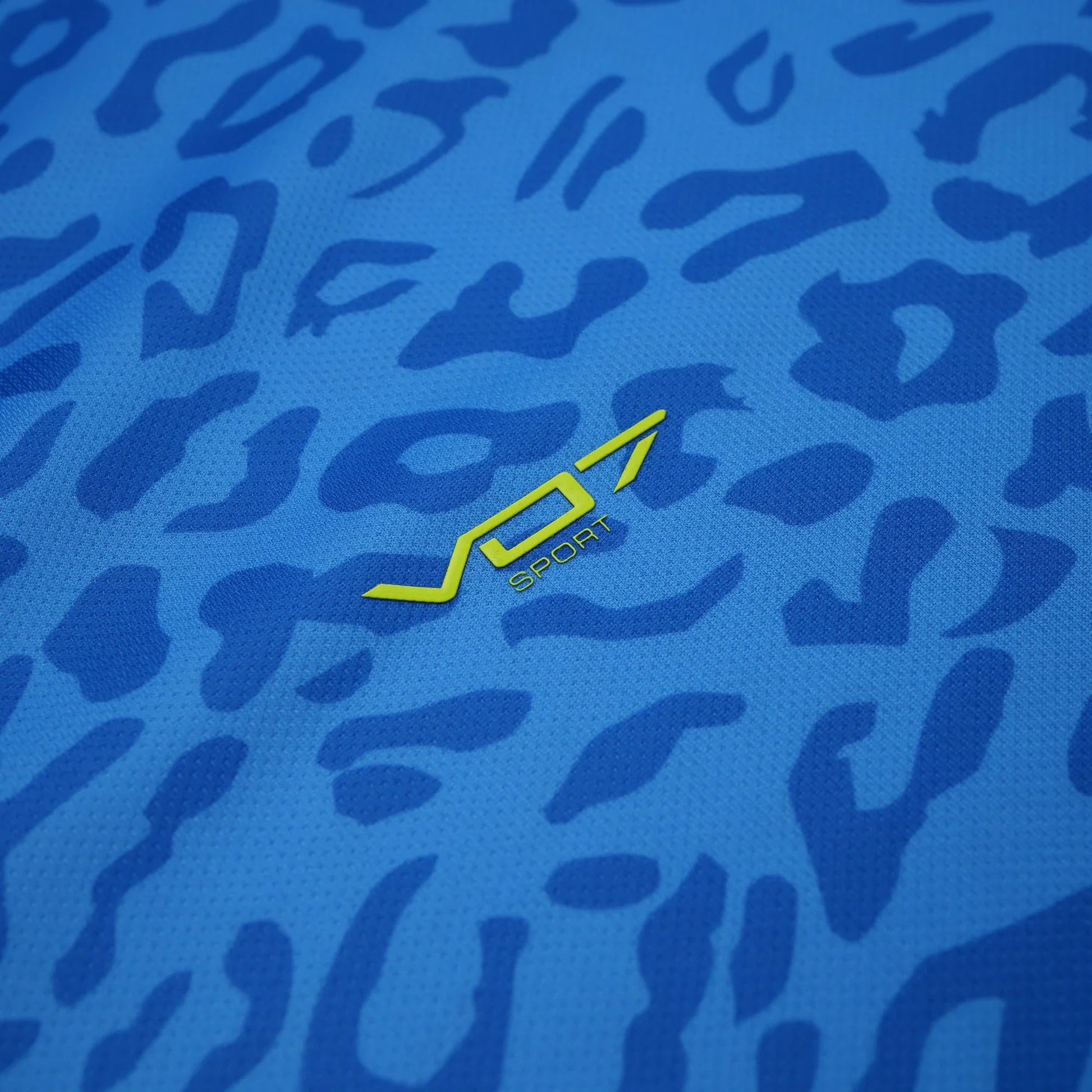Maillot de sport VO7 bleu avec motif léopard ton sur ton et logo jaune citron central en relief. Tissu technique léger.