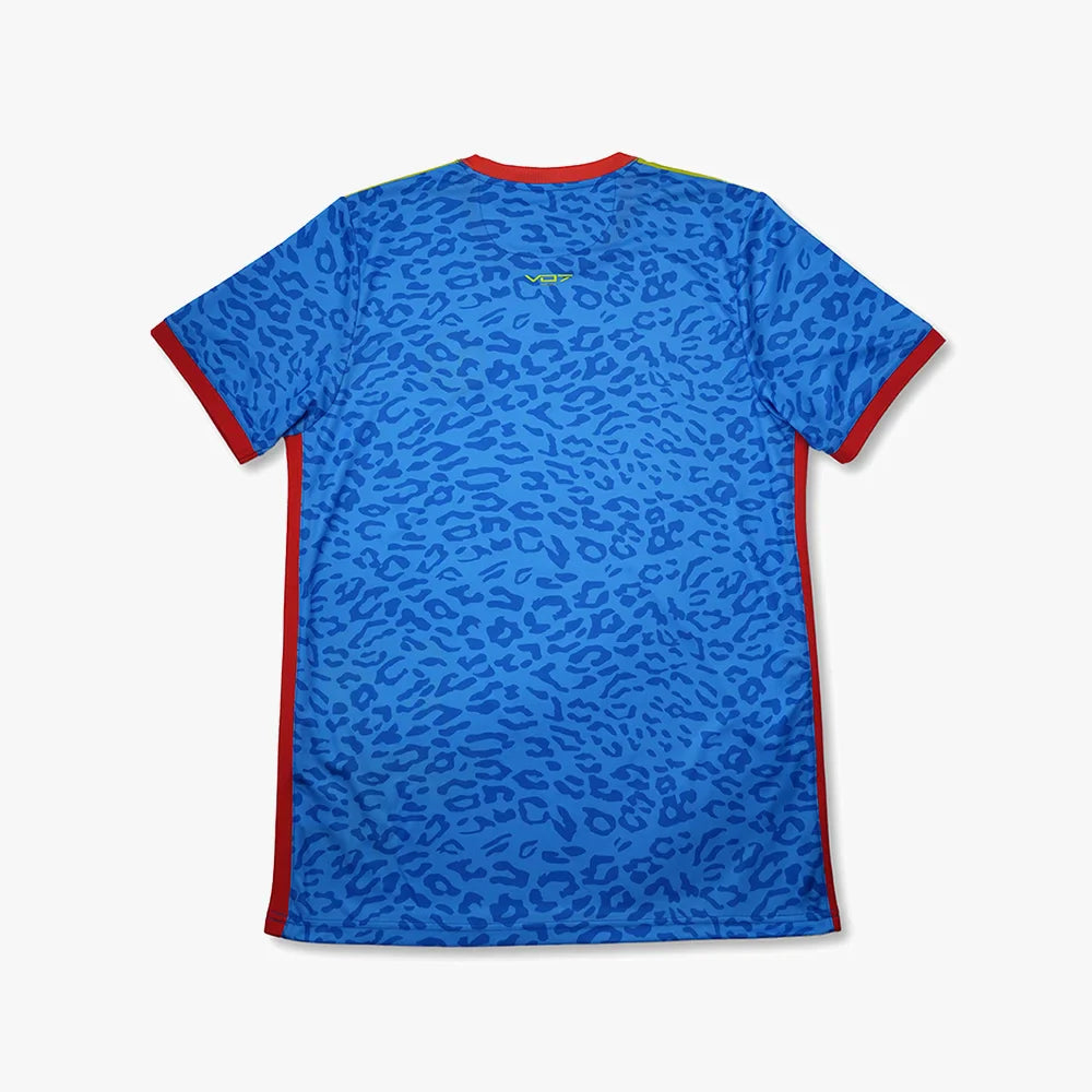 Maillot VO7 bleu à motif léopard, col et bords de manches rouges, coupe technique légère. Logo VO7 jaune au dos.