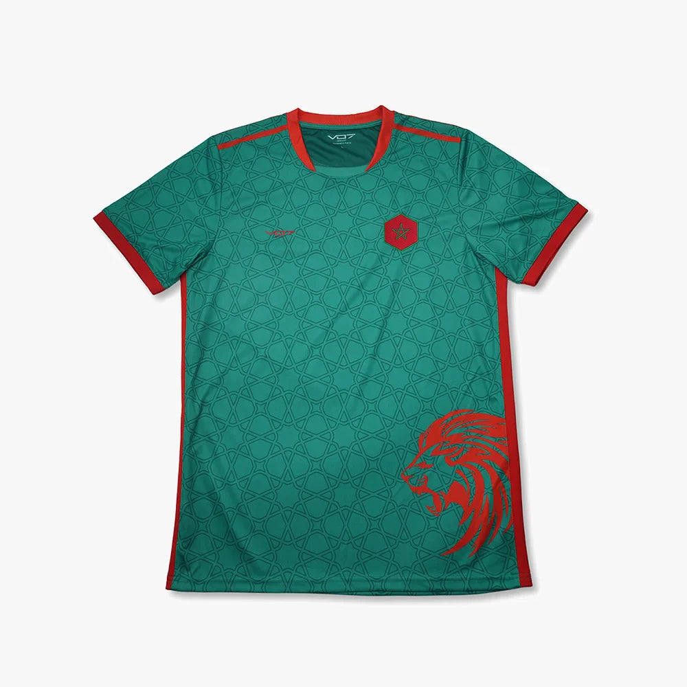 Maillot de foot vert VO7 à motifs géométriques, col et détails rouges, écusson étoile et tête de lion sur le côté.