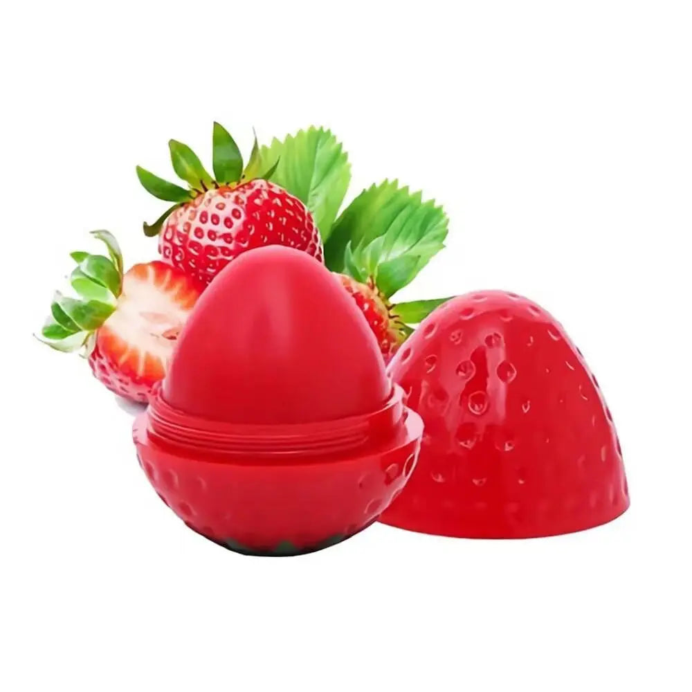 Strawberry-shaped lip butter container in bright red, with open lid and fresh strawberries in the background.